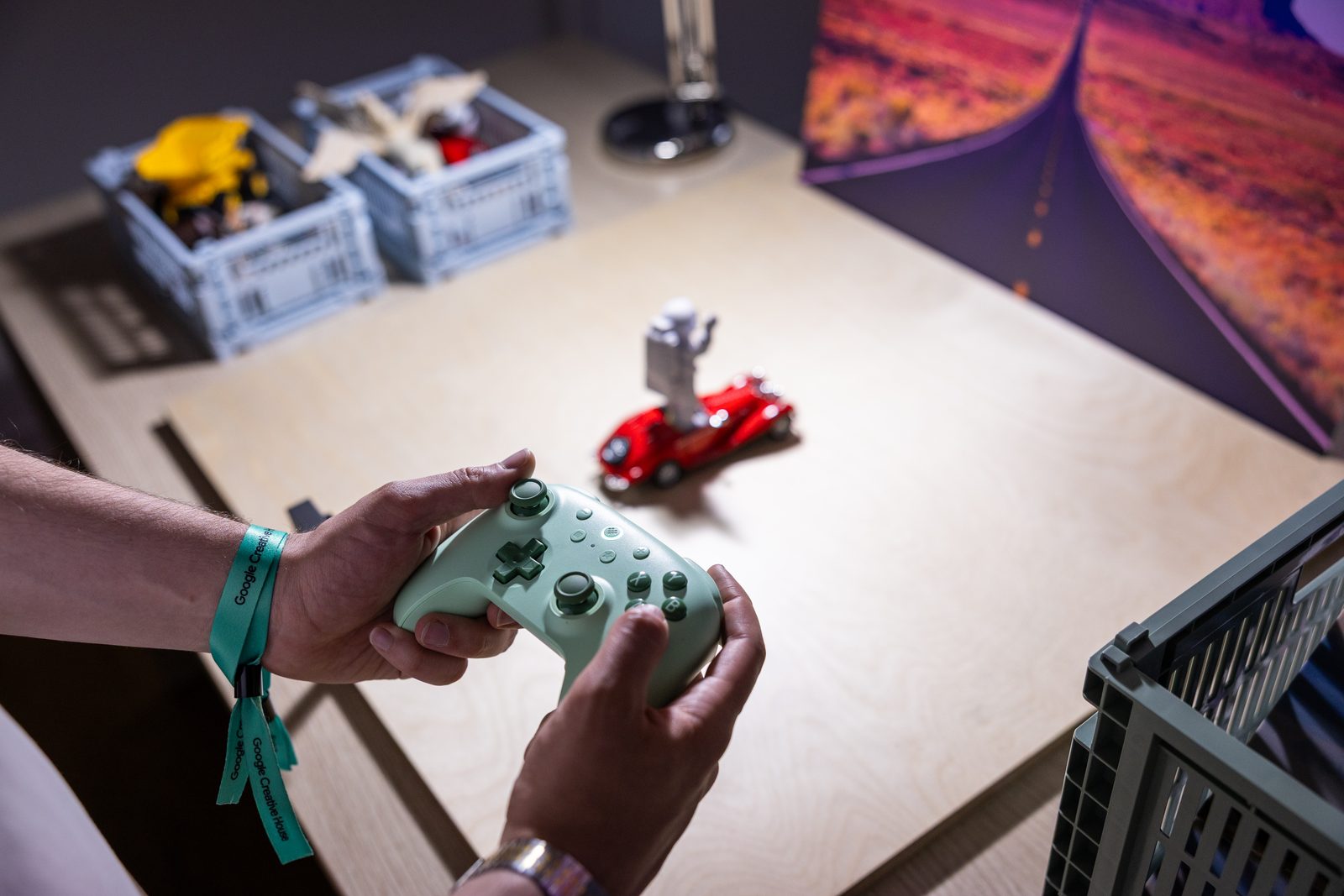 Hands holding the mint controller, toy car with robot on the table